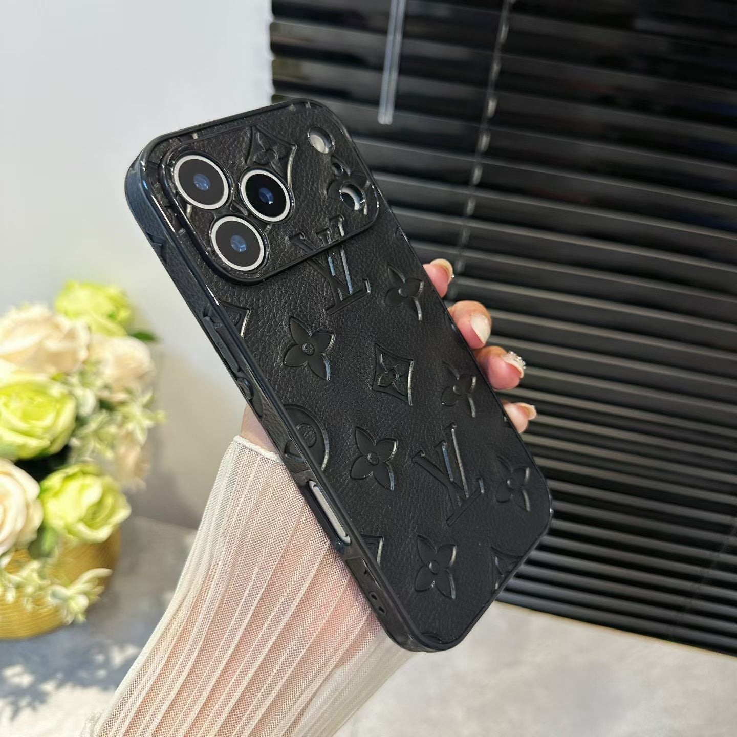 Black phone case with brand logo held by a person, blurred background