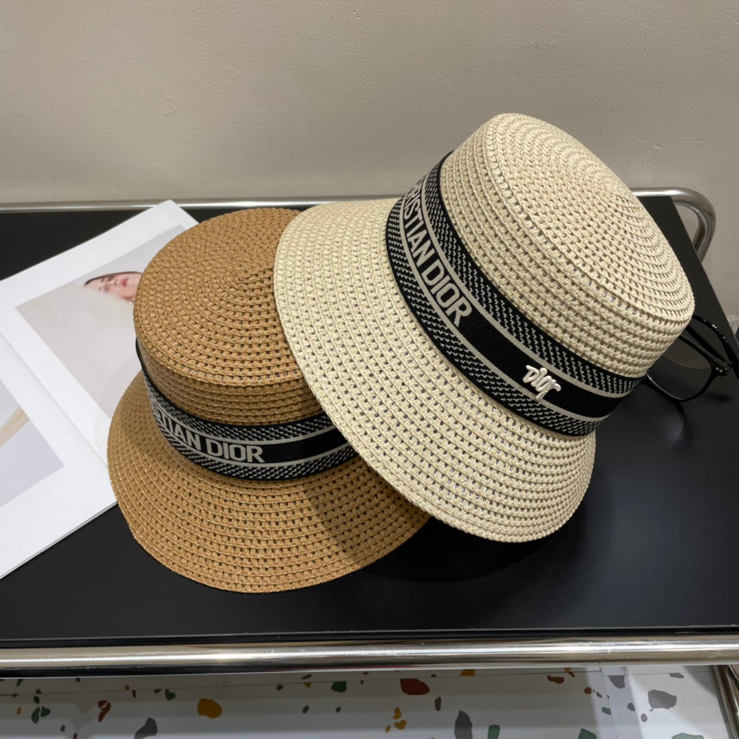Two straw hats with Dior branding on a dark surface.