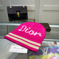 Pink Dior beanie with a visible brand tag on a reflective surface.
