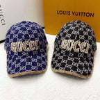 Two Gucci hats with logo patterns on a white surface with a Louis Vuitton box in the background.