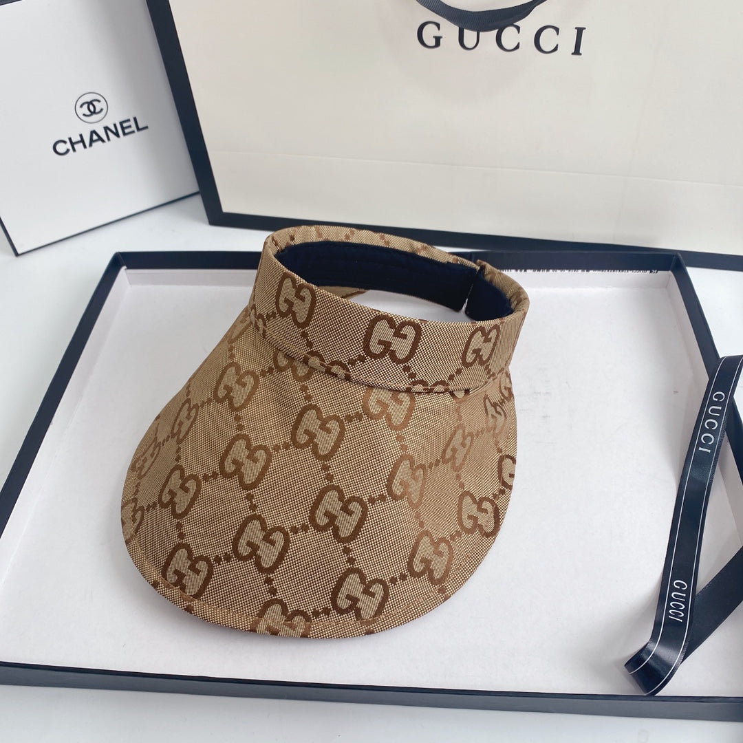 Beige visor with Gucci logo on a white surface with Gucci and Chanel branding in the background.