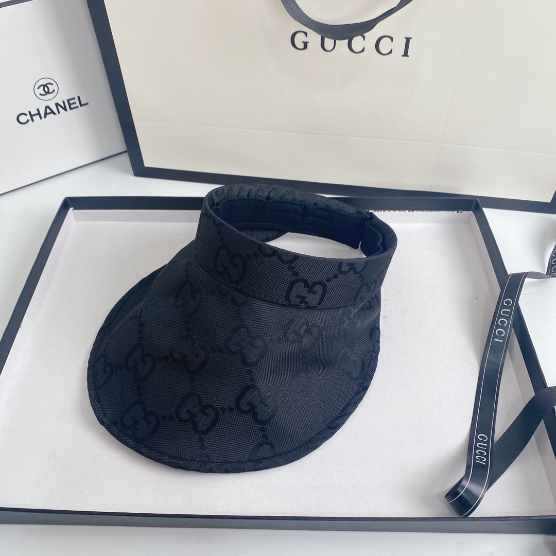Black visor with Gucci logo on a white surface with Gucci packaging.