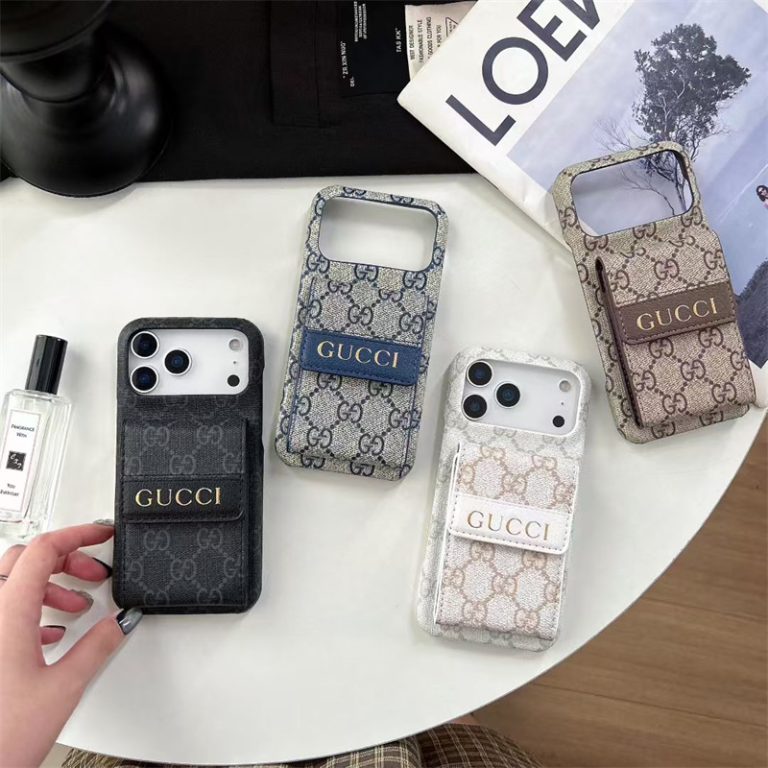 Four Gucci phone cases on a table with a hand reaching for one of them.