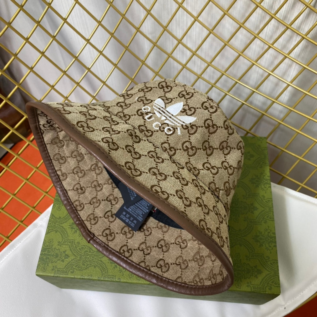 Bucket hat with Gucci pattern and Adidas logo on a green box against a gold grid background