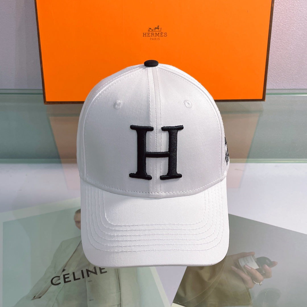 White cap with black 'H' logo in front of a Hermes box