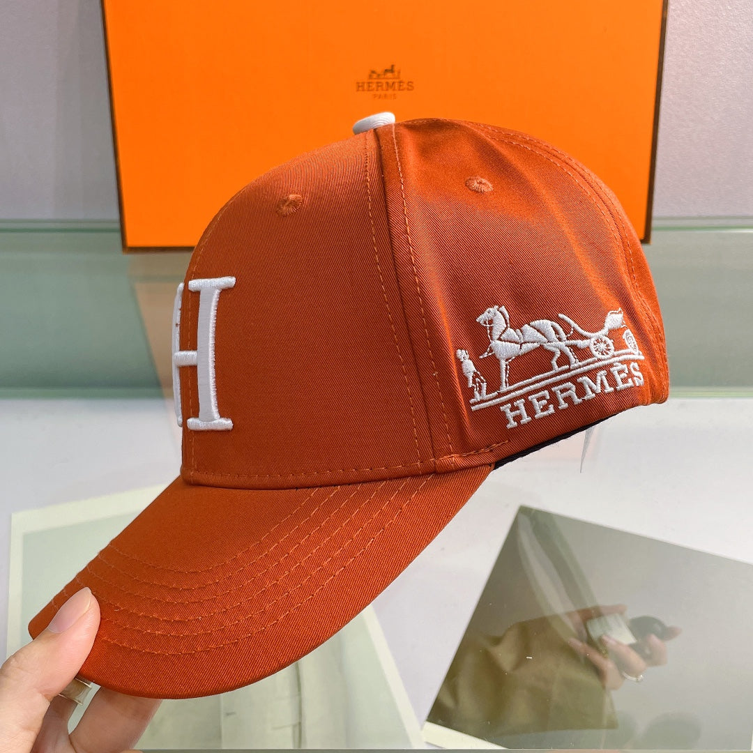 Orange Hermes cap with logo held by a hand, orange box in the background