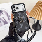 Louis Vuitton phone case with strap held by a hand on a light background