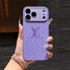 Purple Louis Vuitton phone case held by a hand with manicured nails.