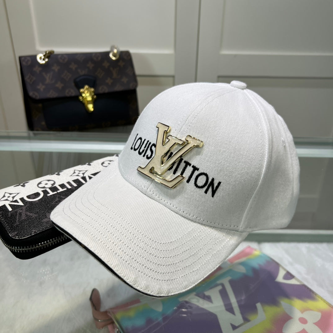 White cap with gold 'Louis Vuitton' logo on a reflective surface with a handbag in the background.
