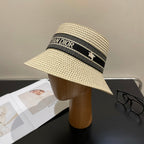 Beige straw hat with black Dior band on a mannequin head against a neutral background