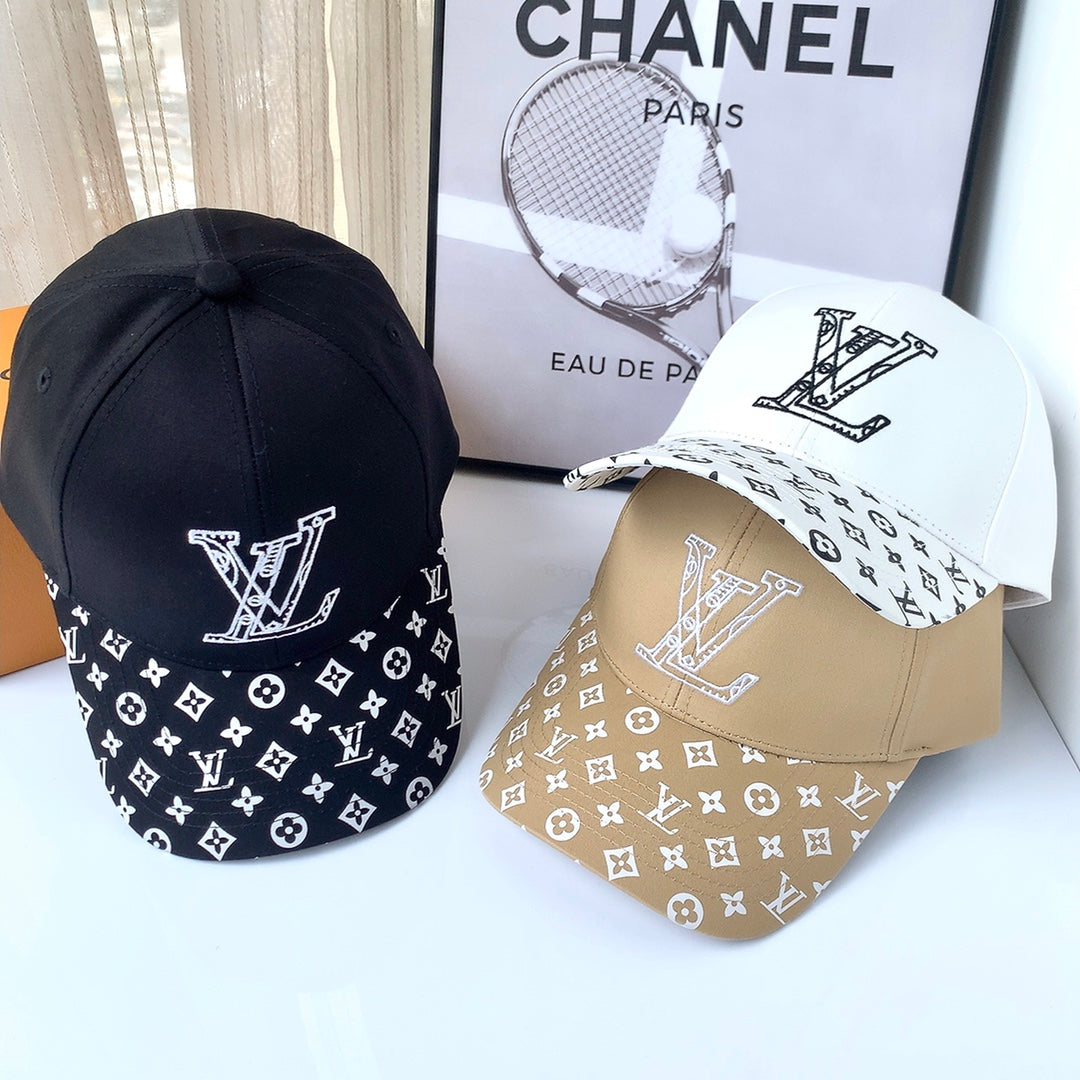 Three Louis Vuitton caps in black, white, and beige with a Chanel book in the background.