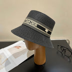 Black straw hat with 'Christian Dior' logo on a mannequin head against a neutral background.