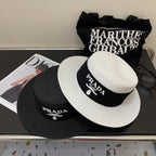 Two hats with Prada branding on a surface with a magazine and sunglasses.