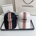 Two Burberry hats with striped designs in a box with Chanel branding.