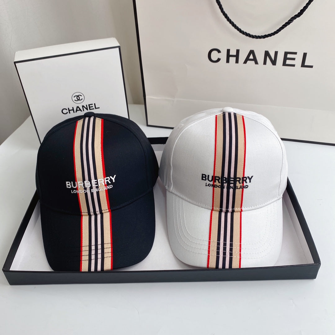 Two Burberry hats with striped designs in a box with Chanel branding.