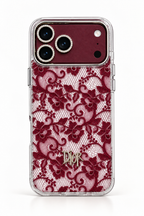 A Dior iPhone case featuring a burgundy lace pattern over a clear mesh backing, with a gold-tone Dior logo at the bottom and a matching burgundy camera ring.