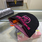 Black beanie with pink text on a colorful box with a mirror reflecting a Louis Vuitton bag.