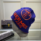 Blue beanie with orange 'Hermes Paris' text on a mannequin head, with Louis Vuitton bags in the background.