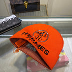 Orange Hermes cap on a glass surface with a handbag in the background