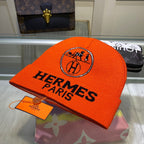 Orange Hermes Paris beanie with logo on a reflective surface
