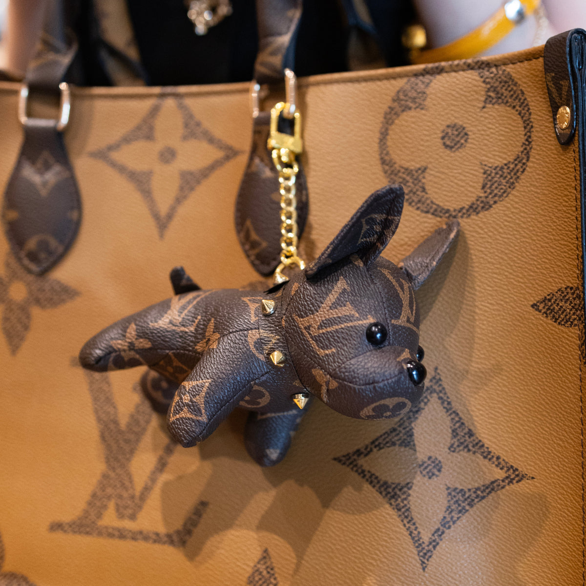 Louis Vuitton monogram puppy keychain styled as a luxury bag charm on monogram handbag