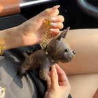 Louis Vuitton monogram puppy keychain with gold-tone clasp held inside a car