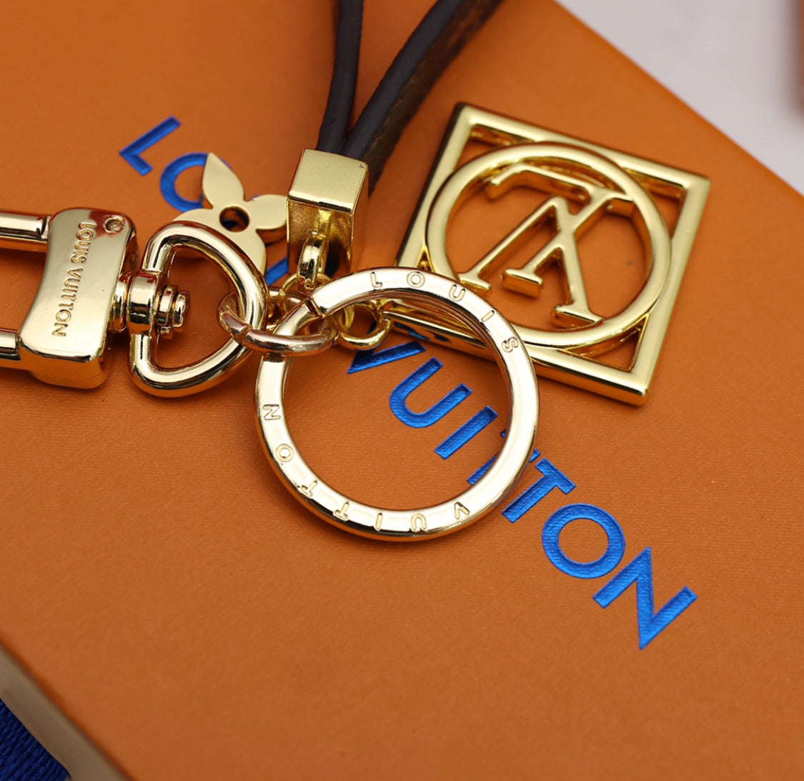 Close-up of Louis Vuitton monogram leather strap keychain with gold-tone clasp, keyring and square charm
