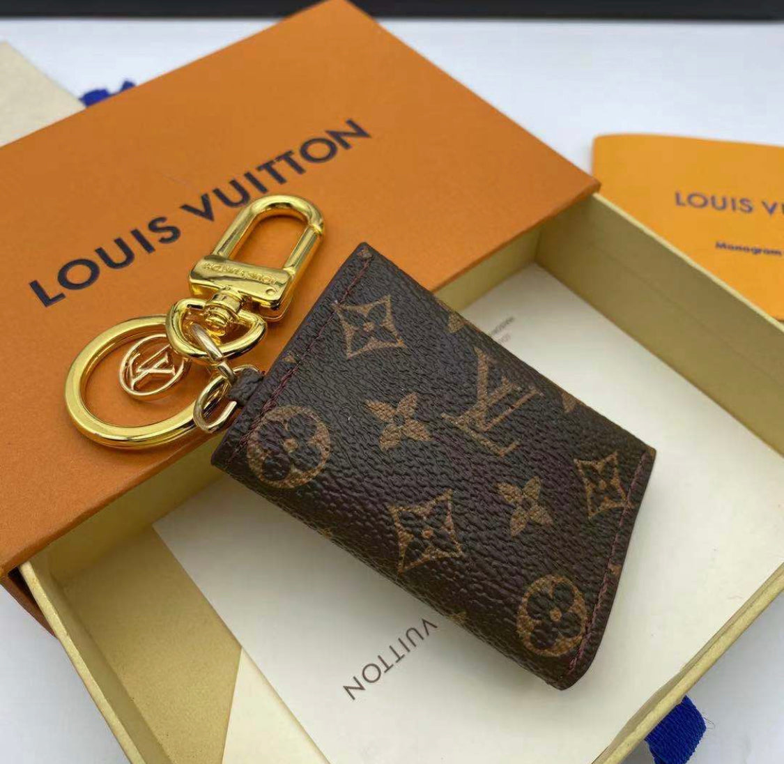 Closed Louis Vuitton monogram mini wallet keychain with gold-tone clasp on luxury packaging