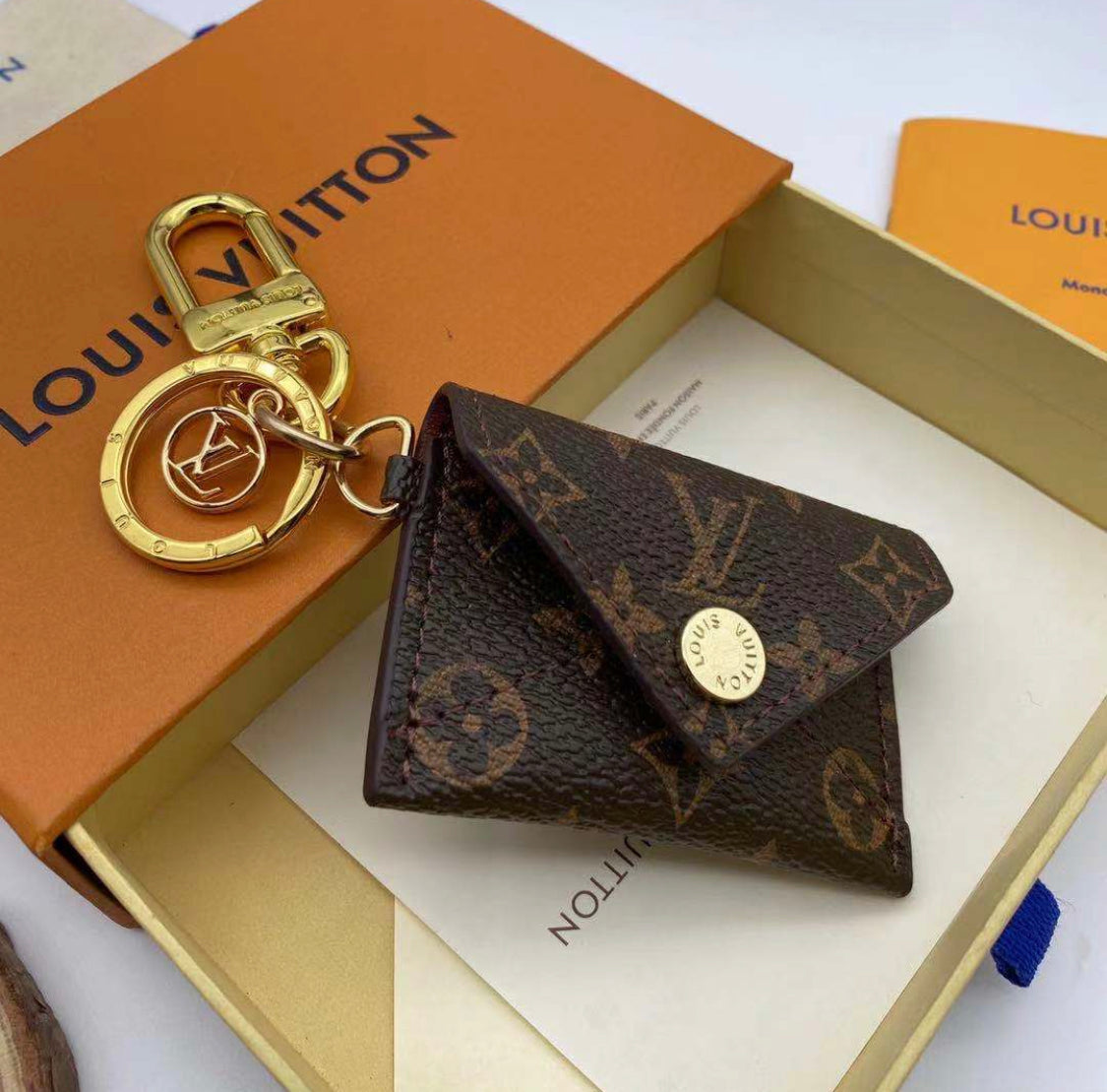 Closed Louis Vuitton monogram mini wallet keychain with gold-tone clasp on luxury packaging