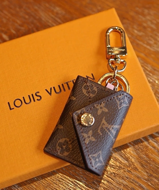 Louis Vuitton monogram mini wallet keychain displayed on orange gift box with gold-tone clasp